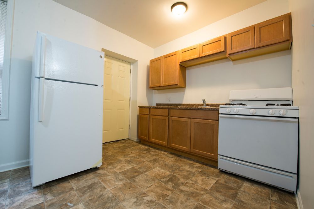 Kitchen with white appliances, brown cabinets, and linoleum flooring.