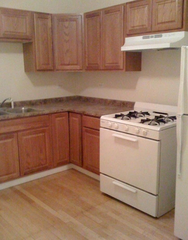 Kitchen with wooden cabinets, a white stove, and light wood flooring.