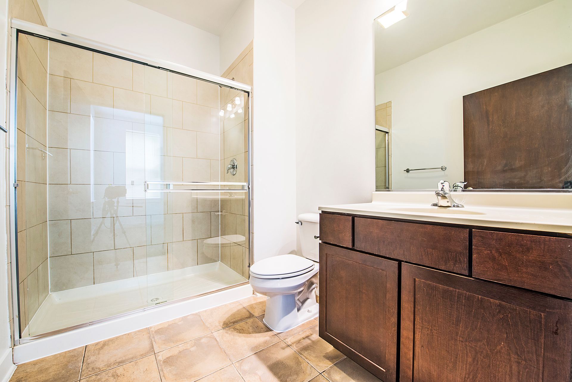 Bathroom with a glass shower, toilet, and dark wood vanity with a white countertop.