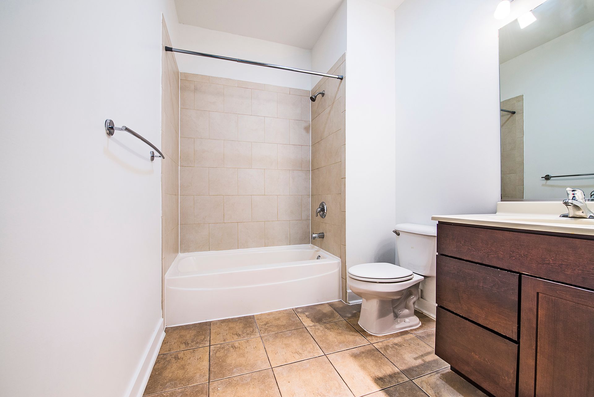 Bathroom with white walls, tiled floor, shower/tub, toilet, and vanity.