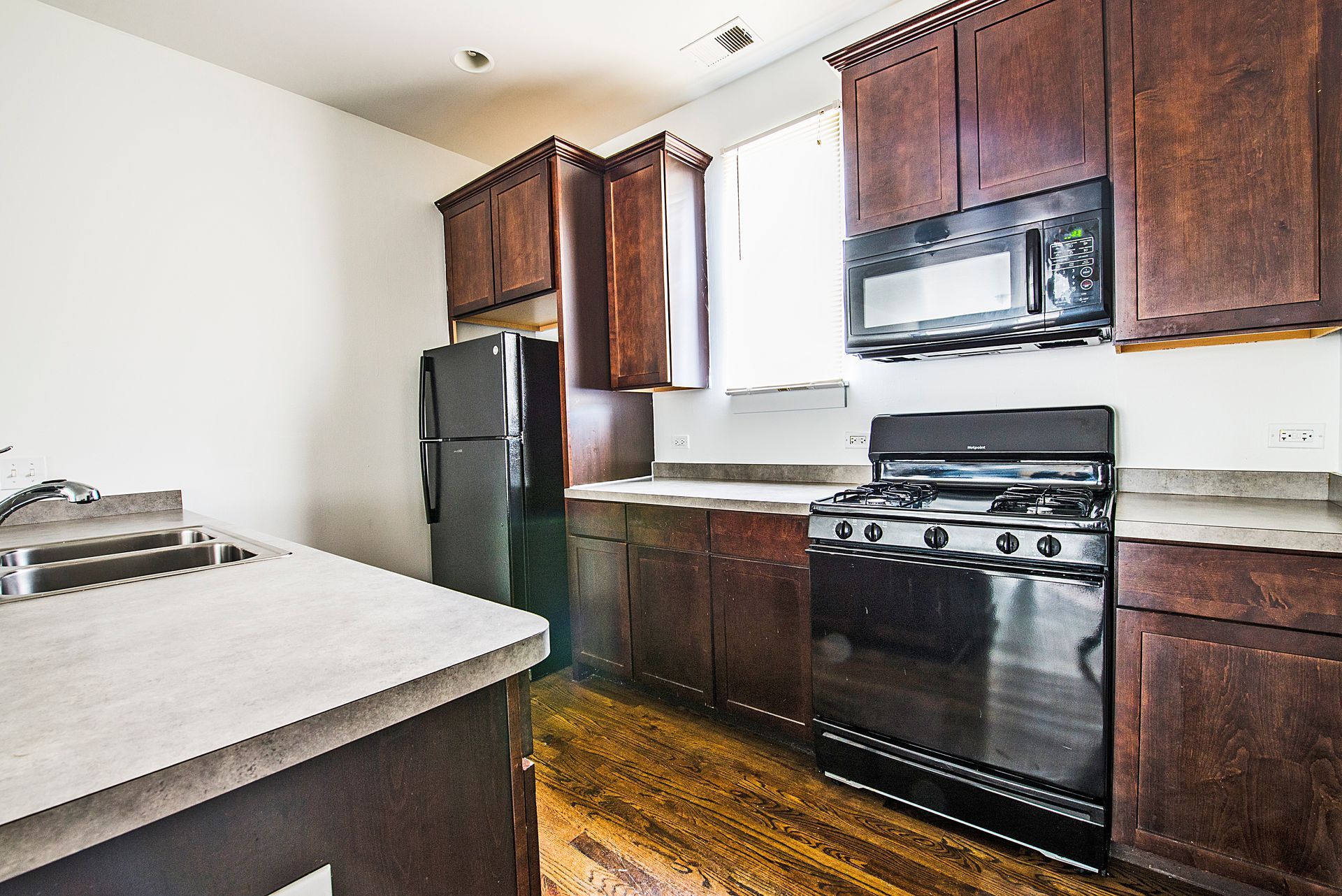 Kitchen with dark brown cabinets, black appliances, and white countertops.