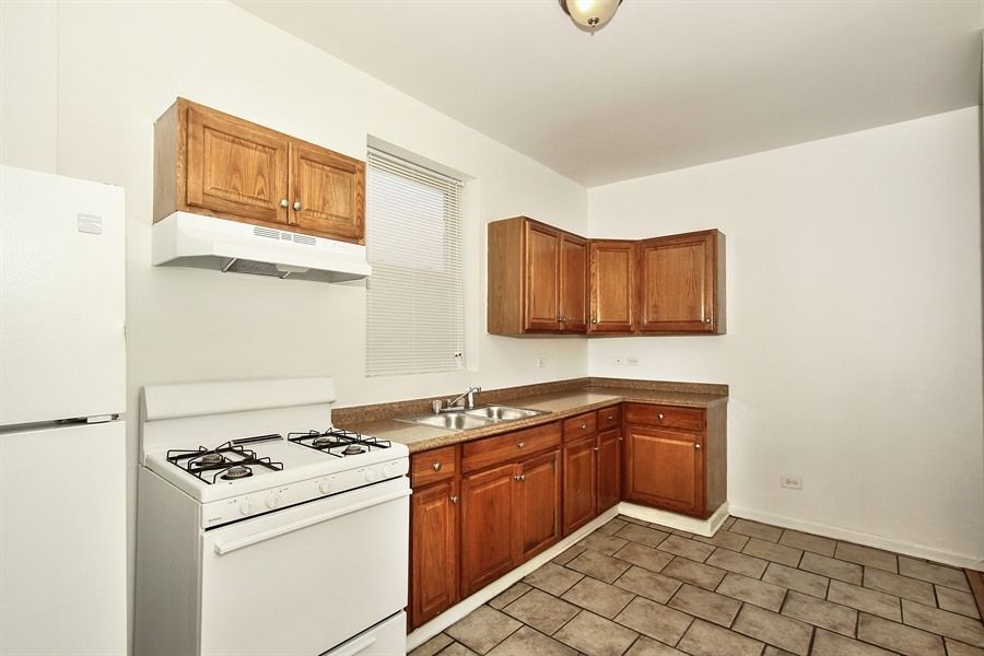 Small kitchen with white appliances, brown cabinets, and a tile floor.