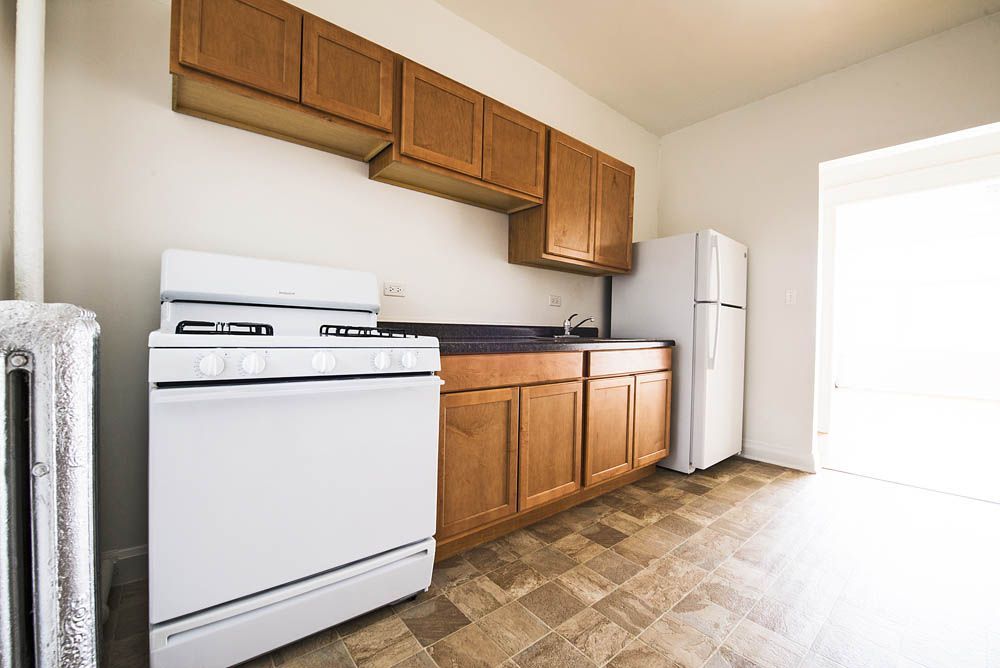 Small kitchen with white appliances, brown cabinets, and linoleum flooring.