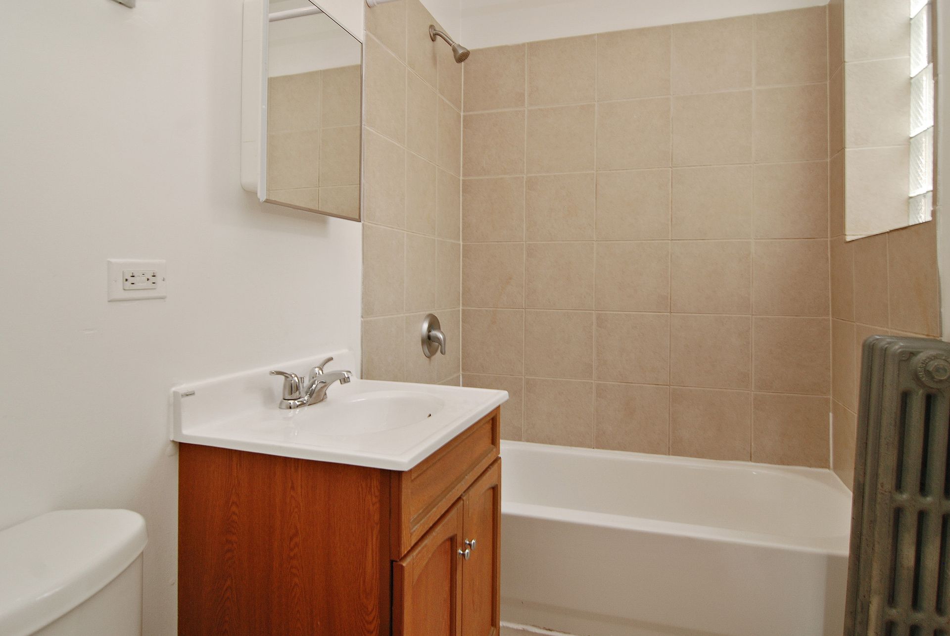 Bathroom with a vanity, toilet, bathtub, and tiled walls.