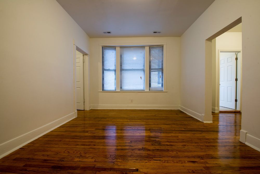Empty room with hardwood floors, a window, and doorways.