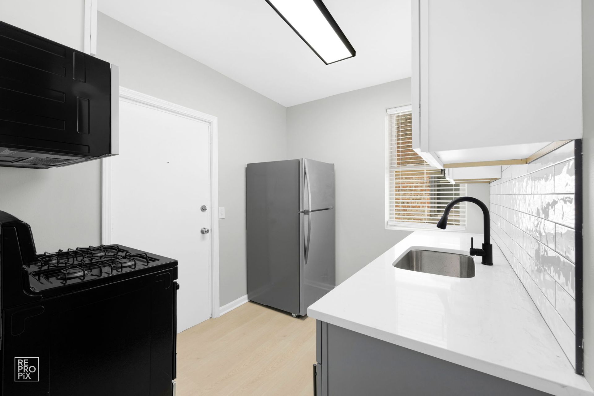 Small kitchen with black appliances, gray walls, and white countertop.