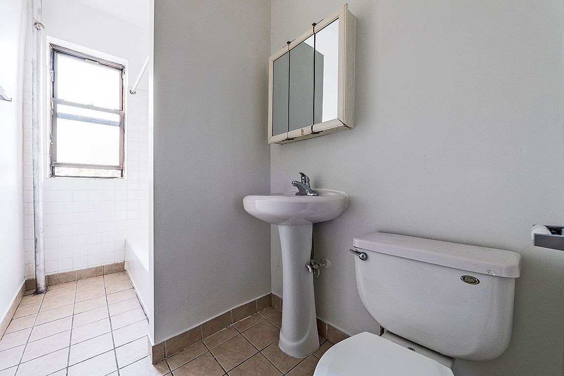 Small white bathroom with a pedestal sink, toilet, medicine cabinet, and window.