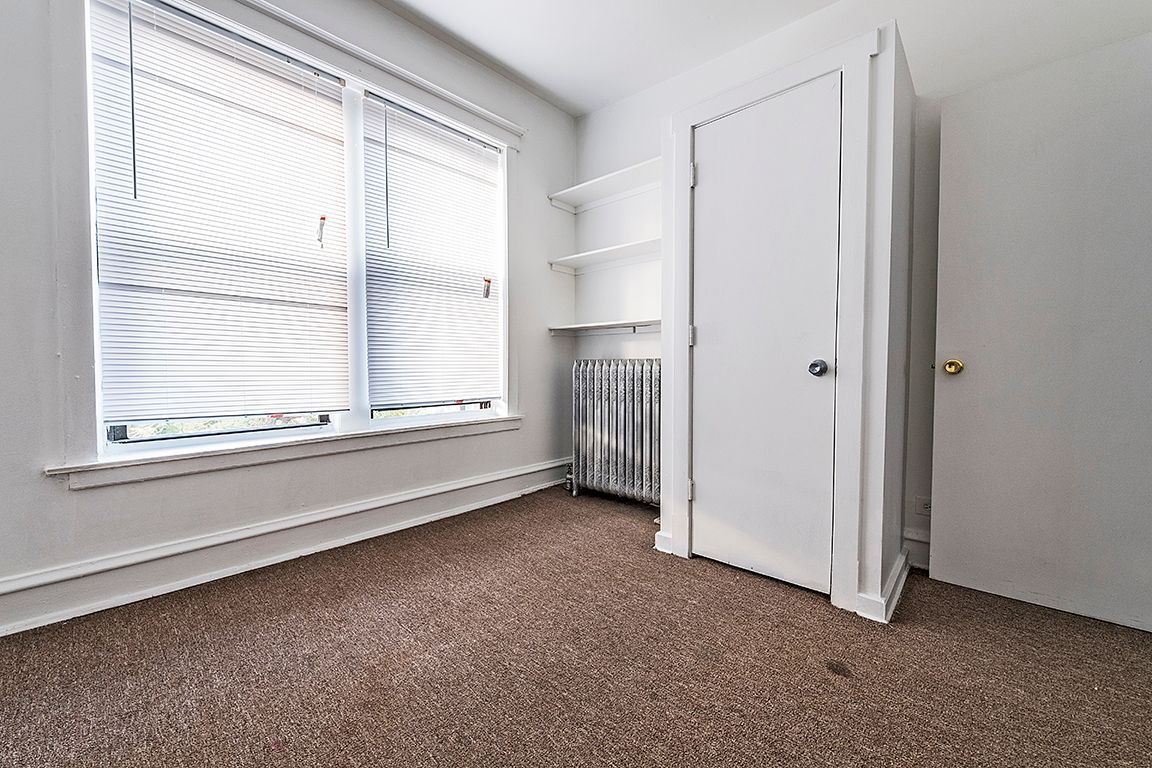 Empty room with carpet, a window with blinds, closet, and radiator.