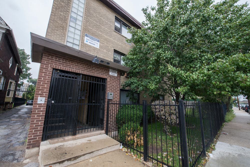 Brick apartment building with black security gate and metal fence.