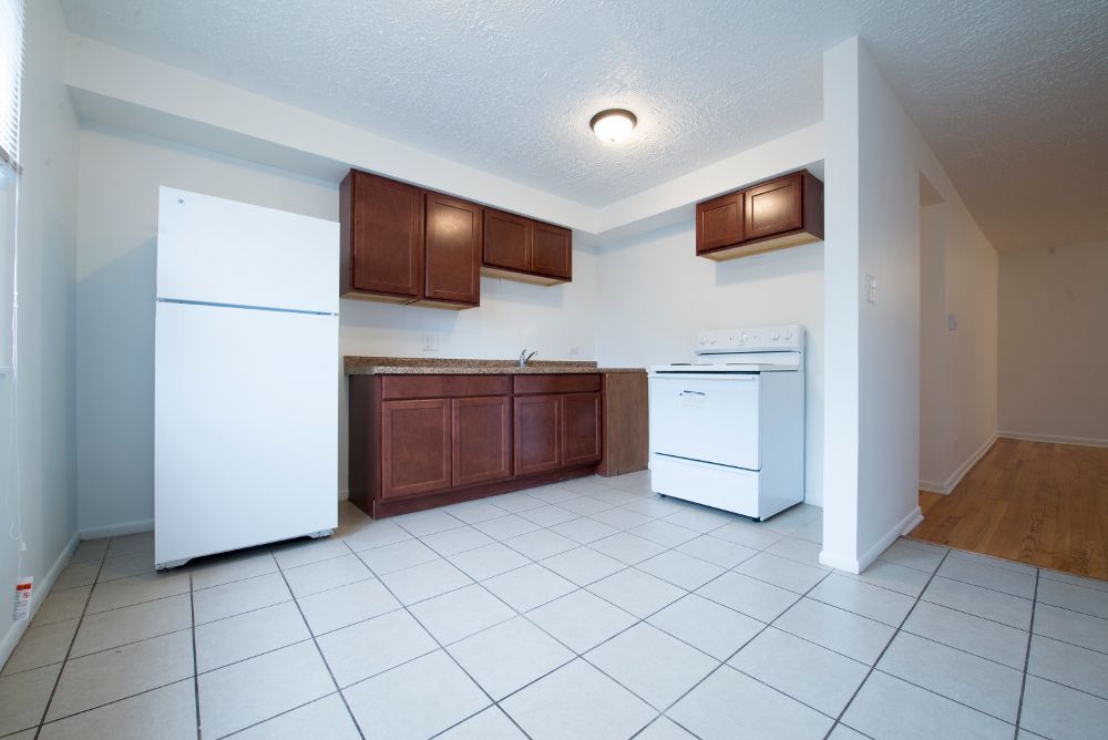 Kitchen with brown cabinets, white appliances, and tiled floor.