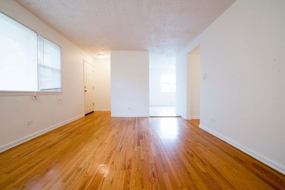 Empty living room with hardwood floors and white walls.