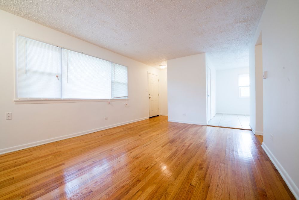 Empty room with hardwood floors, white walls, and a window.