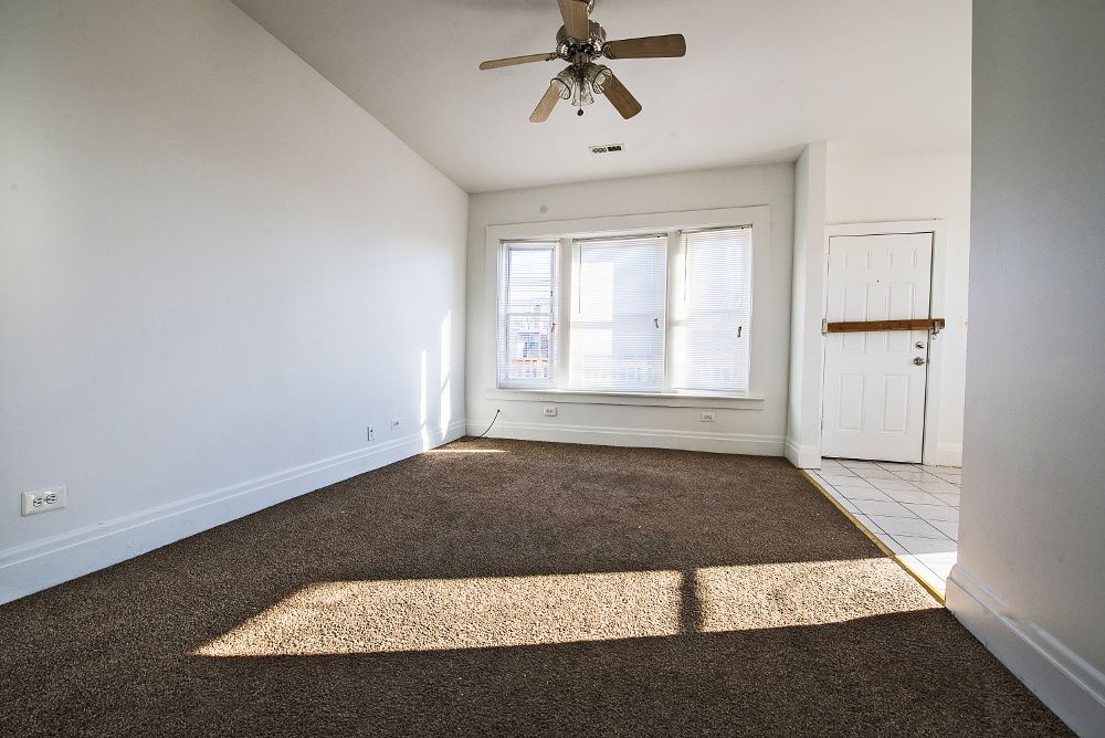 Empty room with brown carpet, white walls, a ceiling fan, and window.