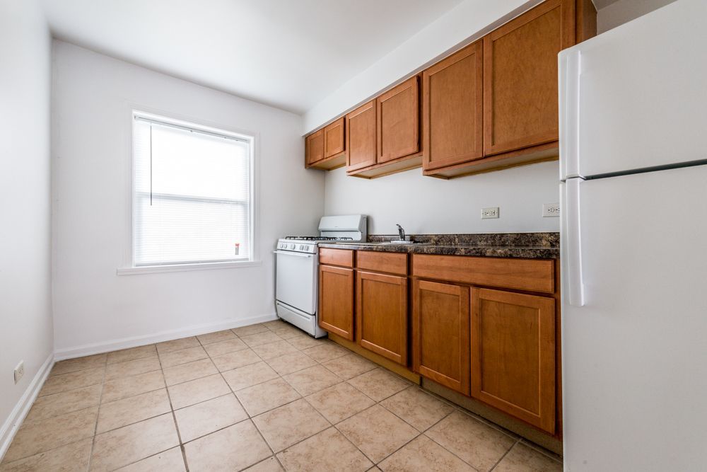 Small kitchen with wood cabinets, white appliances, and a window.