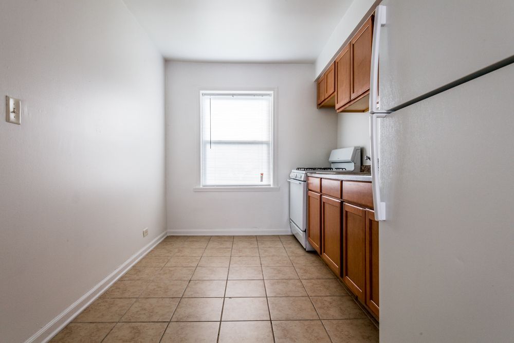 Small kitchen with light brown cabinets, white appliances, and a window.