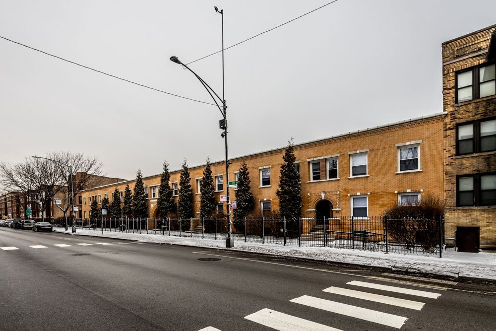 Apartment building on a city street, overcast day. Snow on ground.