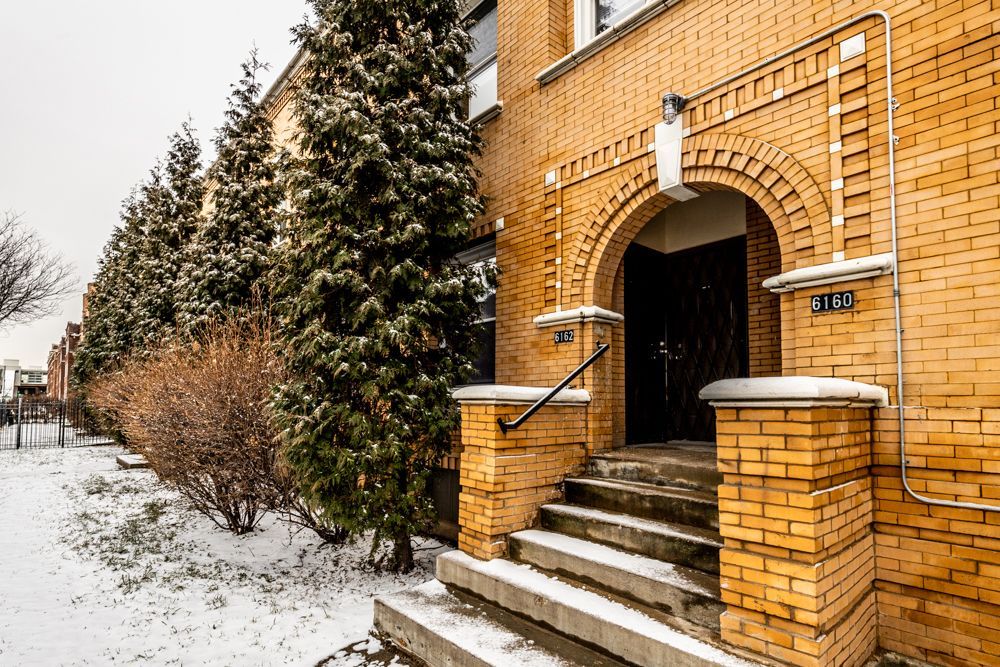 Brick building entrance with archway, steps, and snow-covered ground.