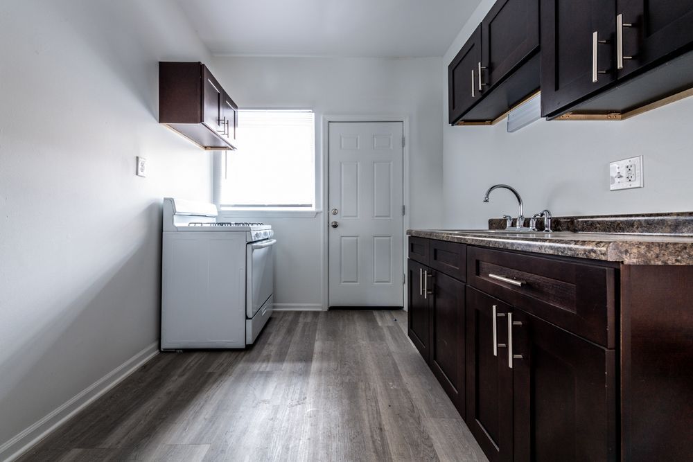 Small kitchen with white appliances, dark brown cabinets, and a window.