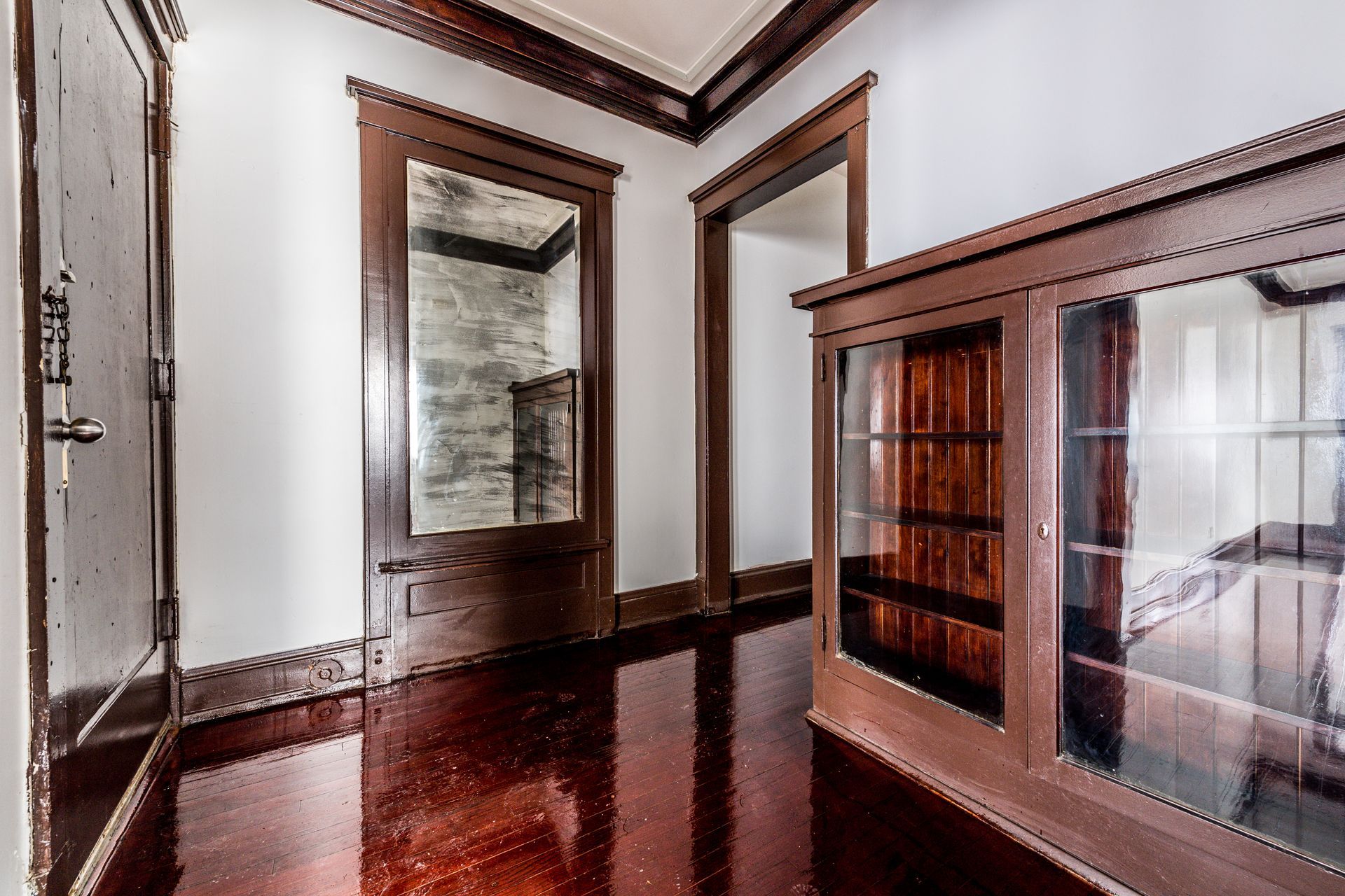 Hallway with dark wood trim, floors, doors, and a built-in display cabinet.