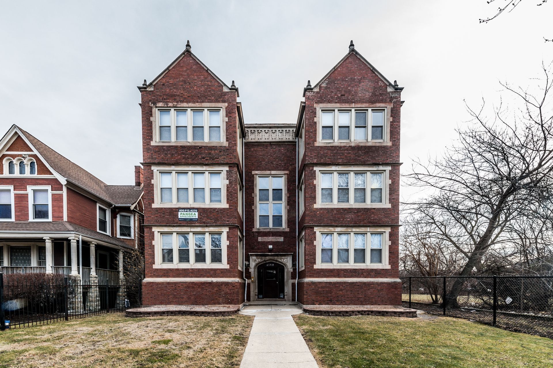 Red brick apartment building with three stories and peaked towers.