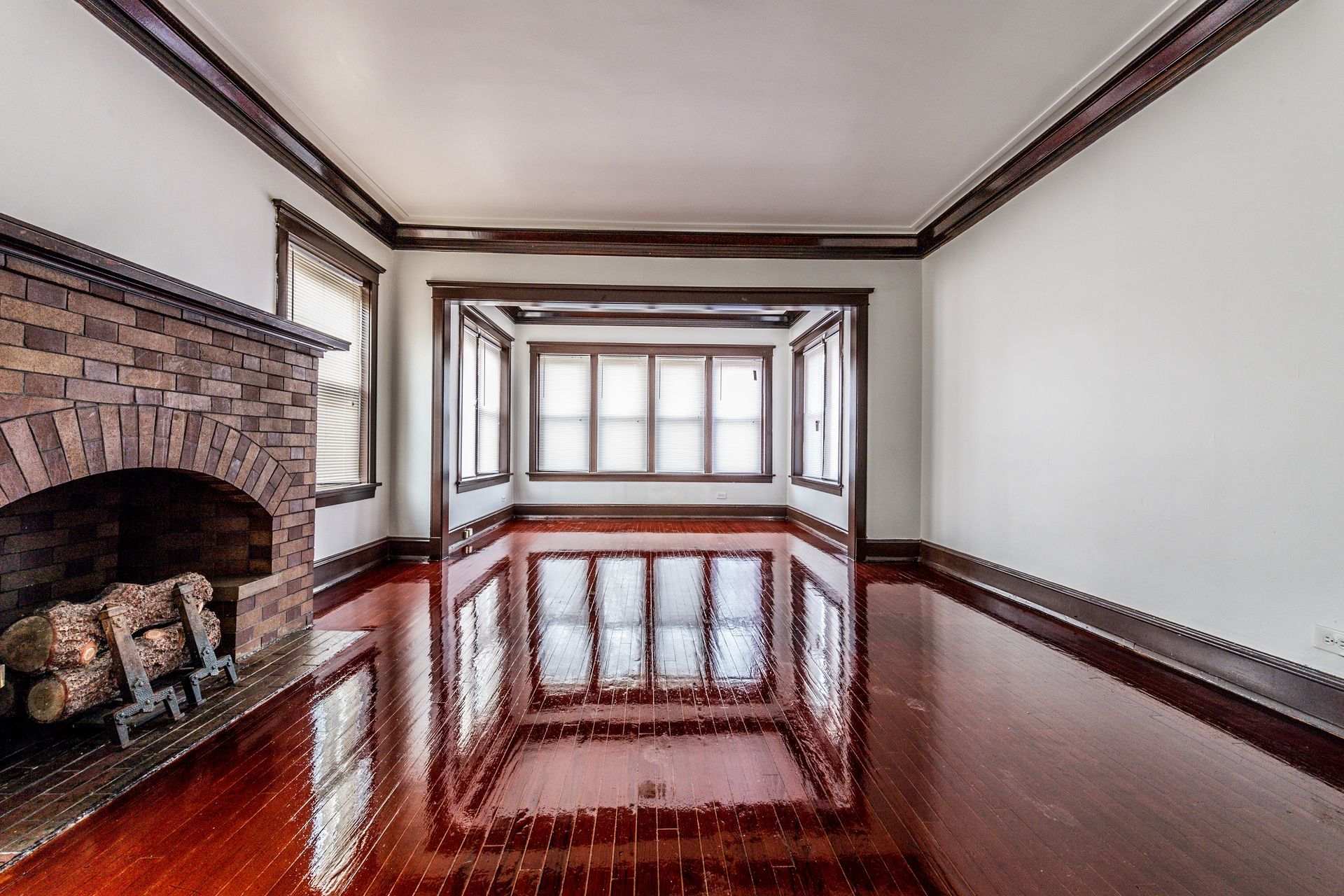 Empty room with hardwood floors, a fireplace, and a bay window.