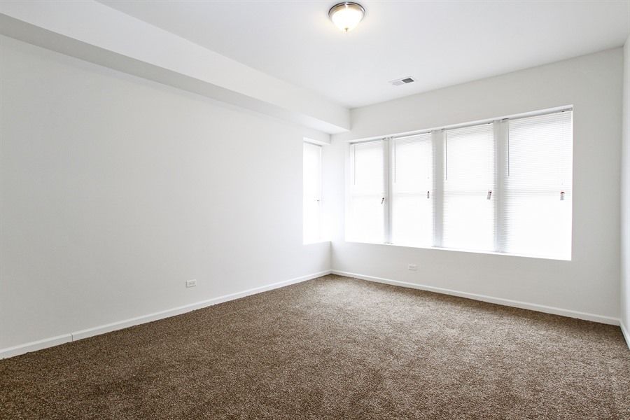 Empty room with brown carpet, white walls, and a multi-pane window with blinds.