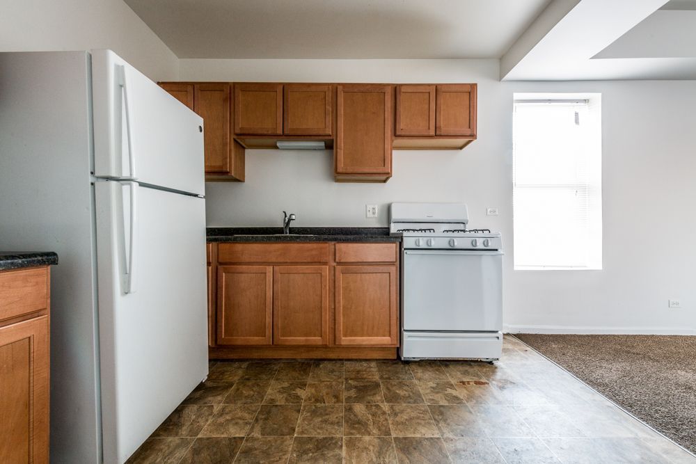 Kitchen with white appliances, brown cabinets, and a window.