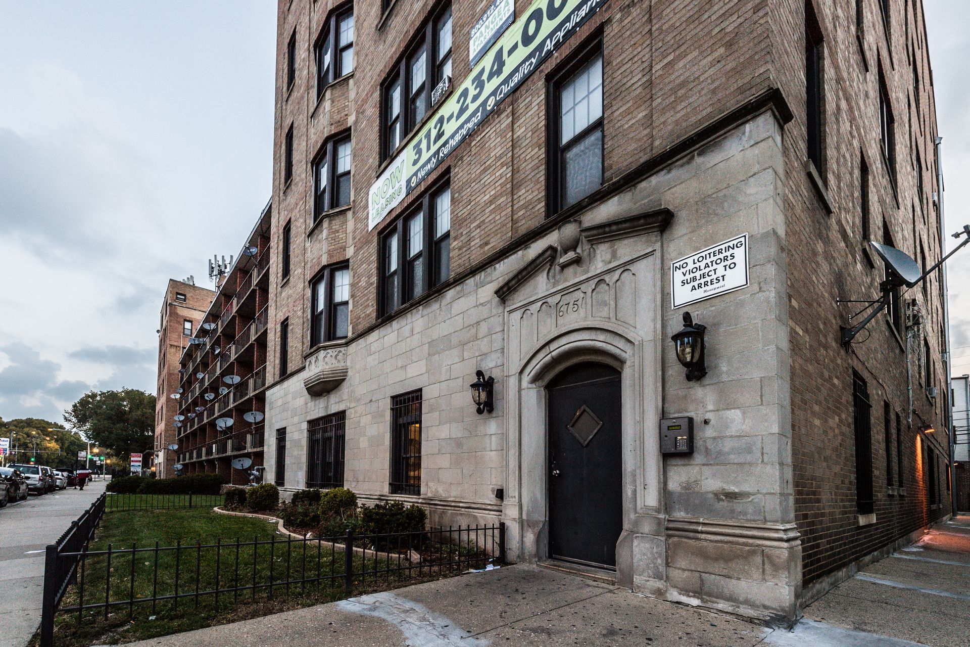 Apartment building entrance with stone facade, dark door, and brick exterior.