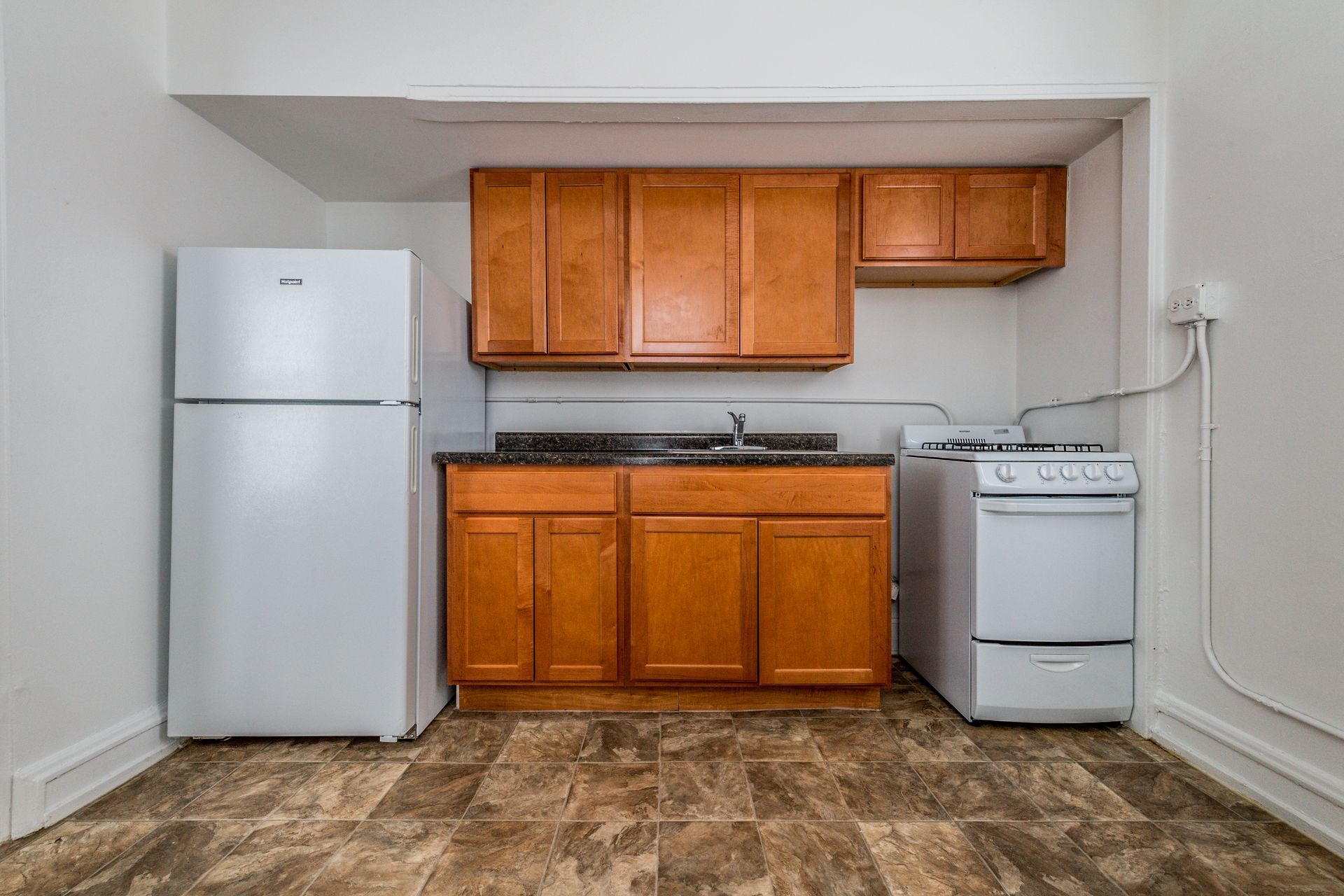Small kitchen with white appliances, brown cabinets, and a stove.