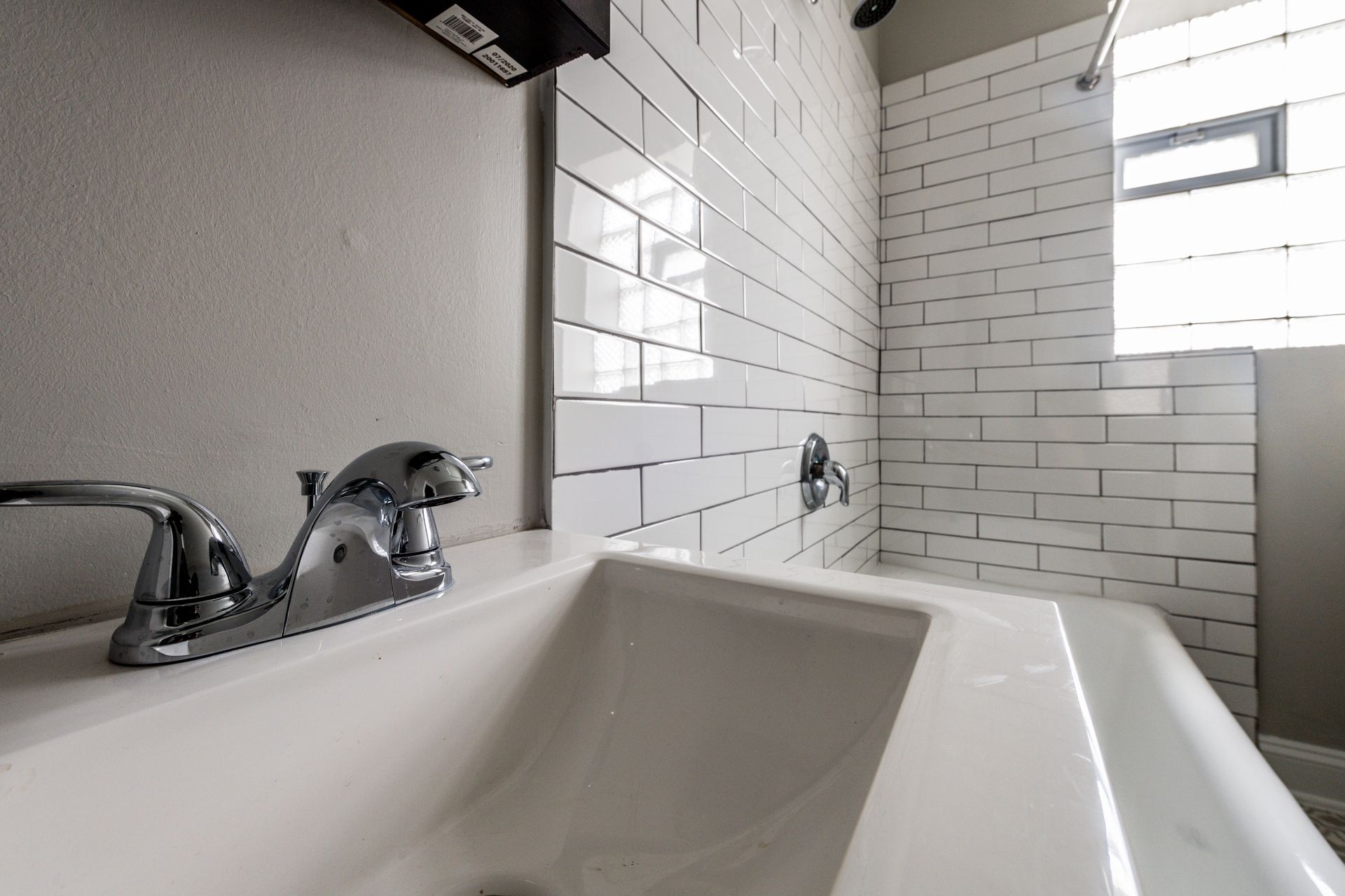 Bathroom with white sink, tile shower, and silver faucet.