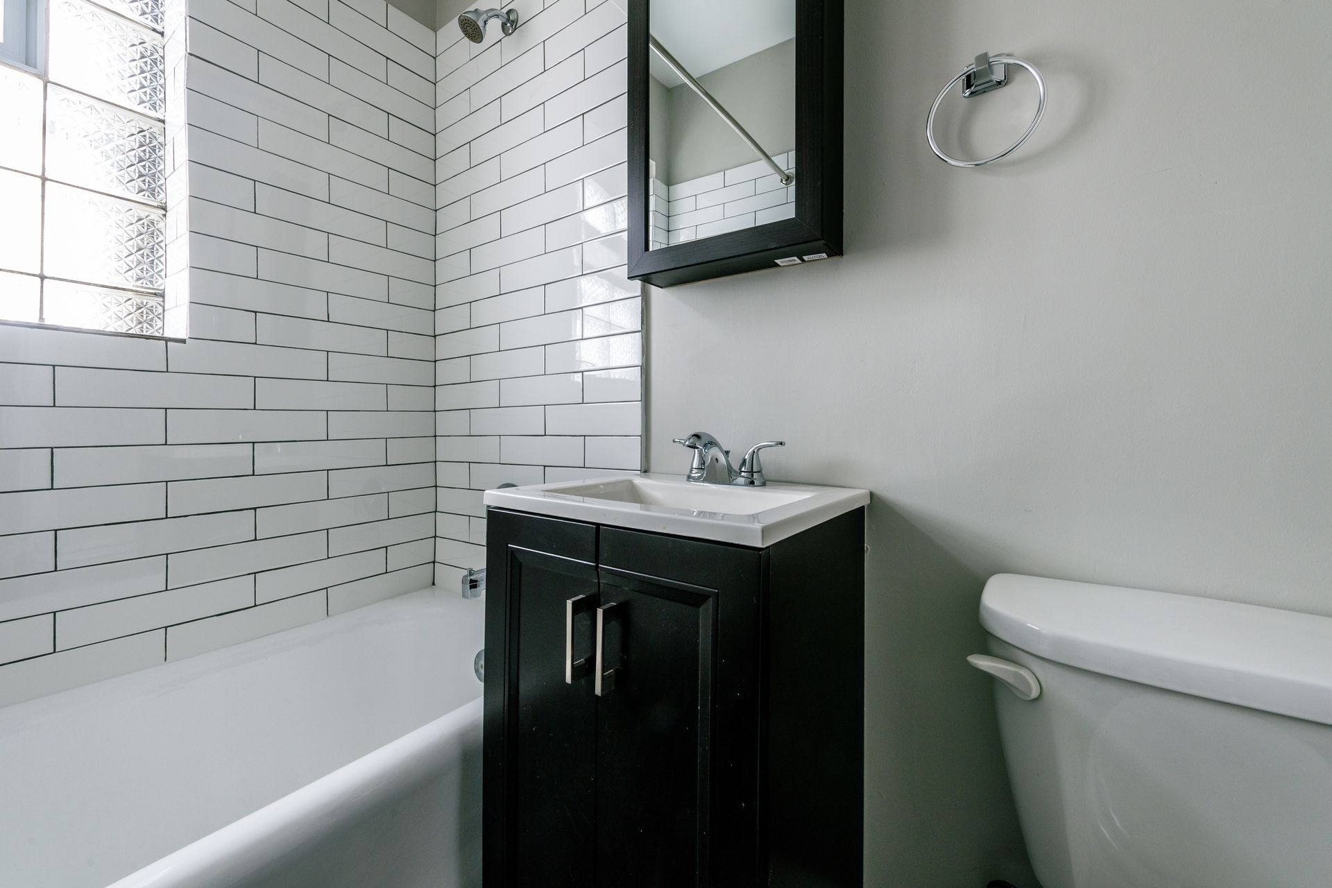 Bathroom with white subway tile, black vanity, and toilet.