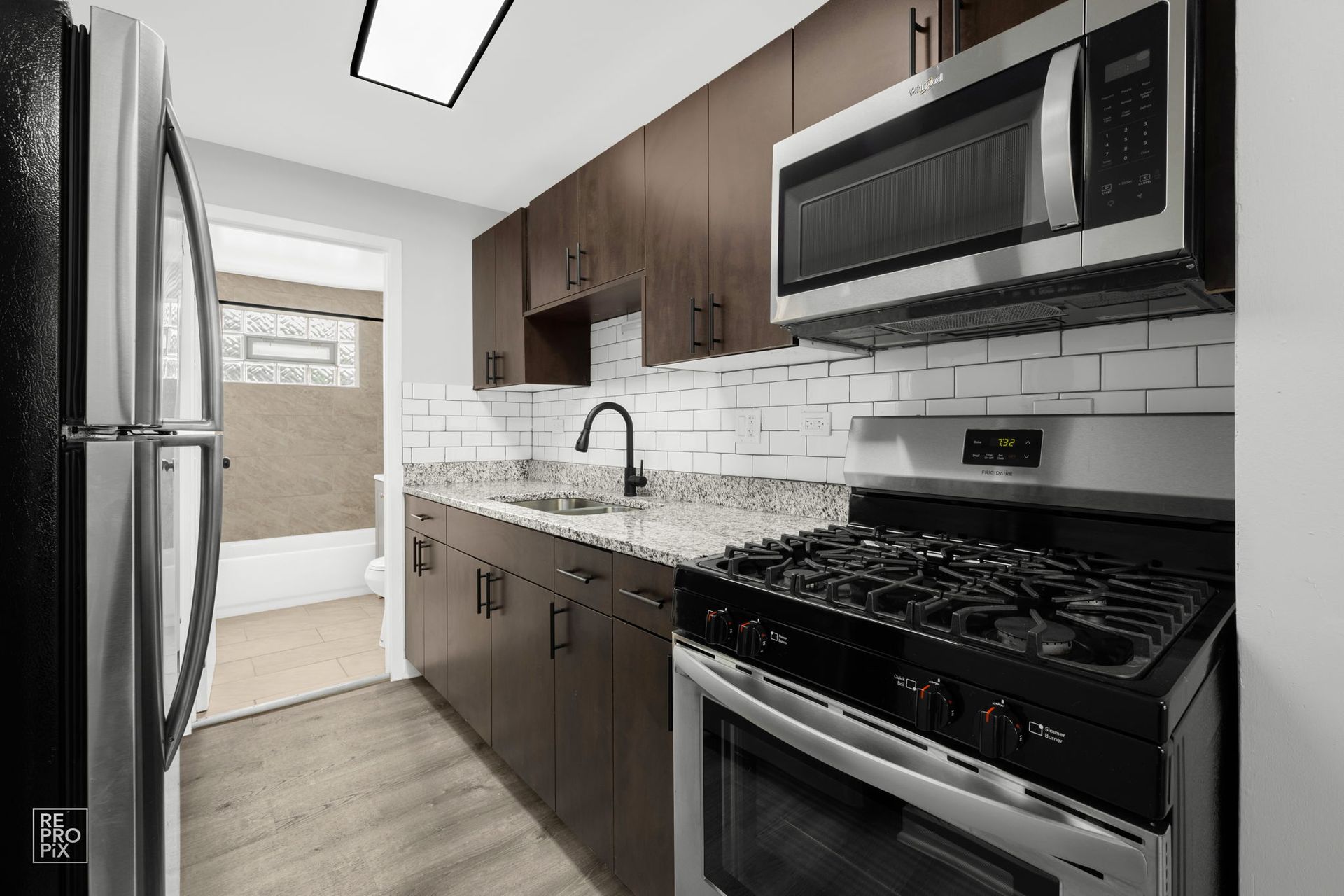 Kitchen with dark wood cabinets, stainless steel appliances, and a tiled backsplash.