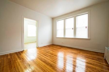 Empty room with hardwood floors, a doorway, and a window with blinds.