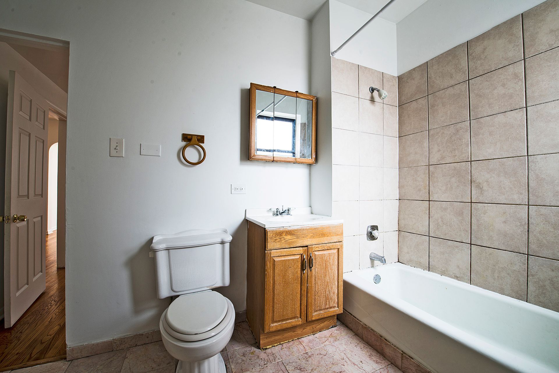 Bathroom with toilet, sink, mirror, bathtub, and tiled walls.
