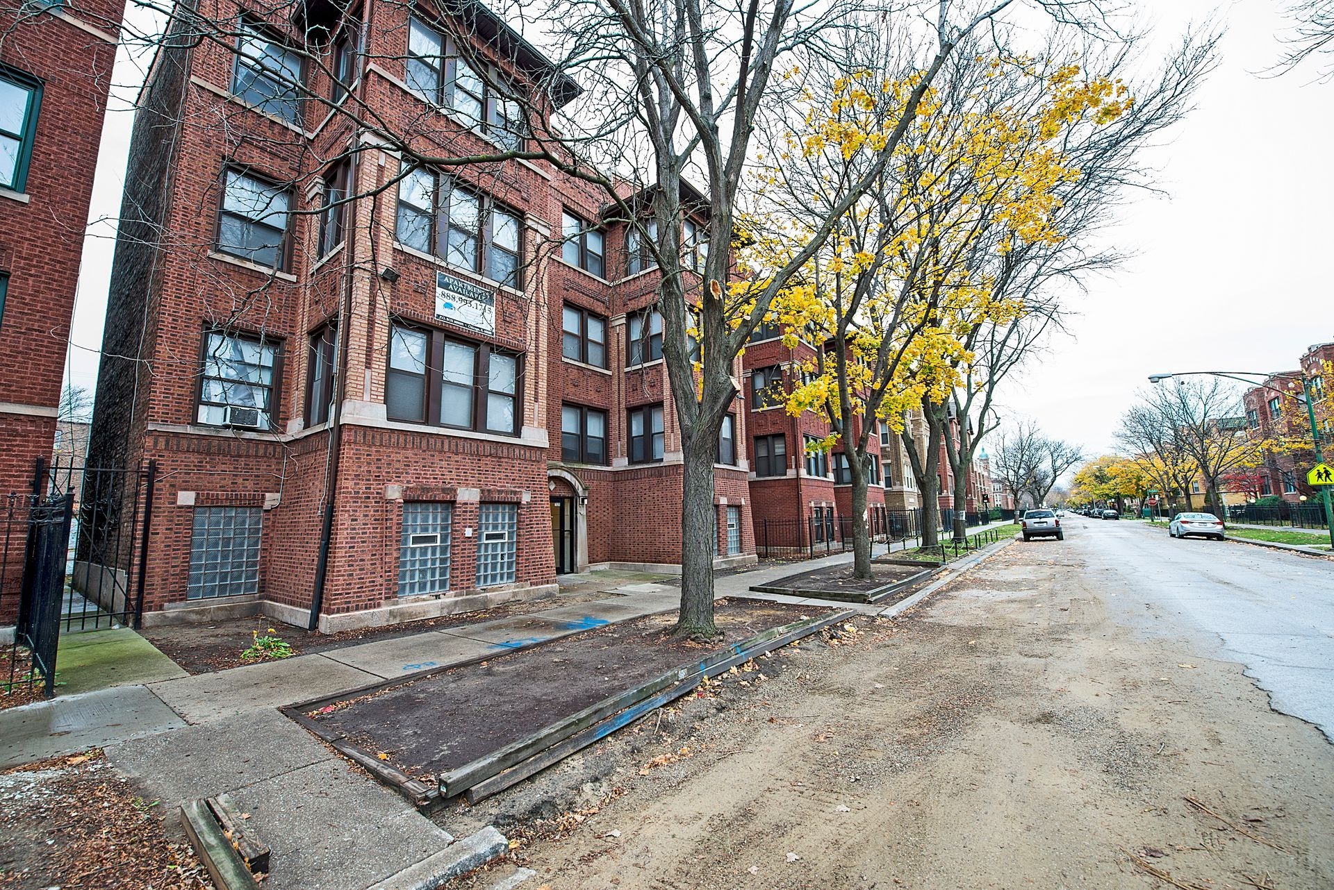 Brick apartment building with trees lining the sidewalk.