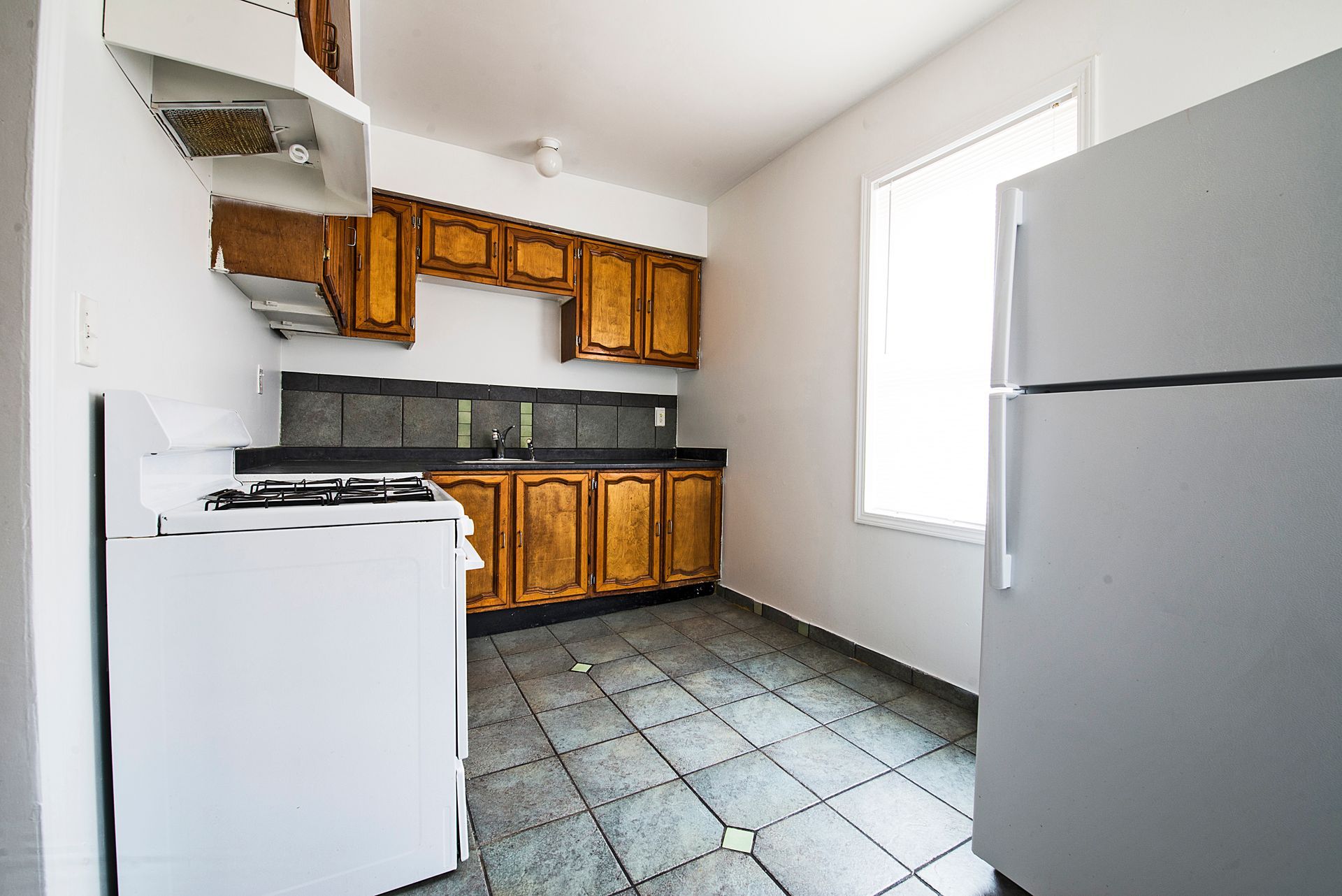 Empty room with hardwood floors, white walls, arched doorway, and a ceiling fan.