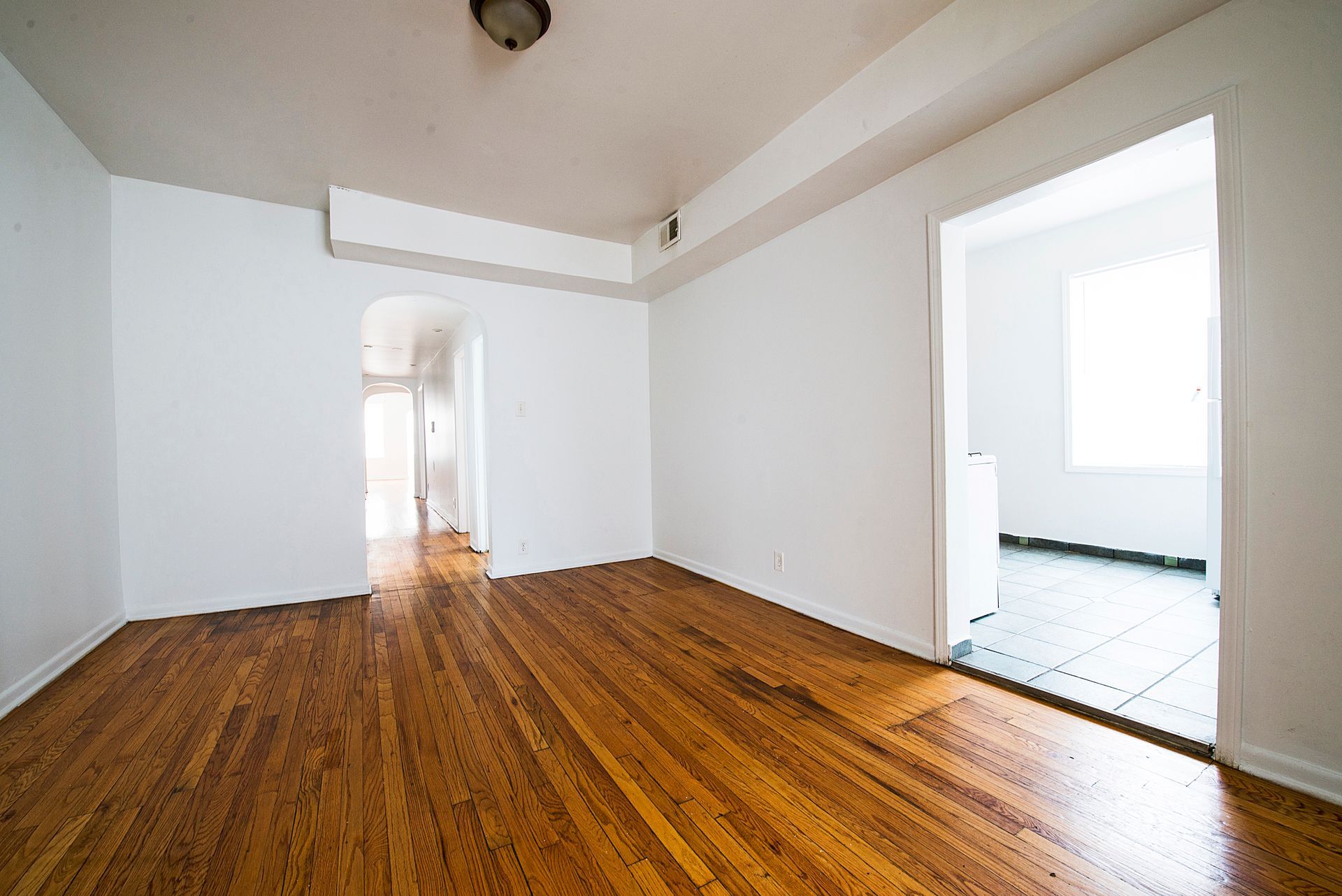 Empty room with hardwood floors, white walls, and an open doorway.