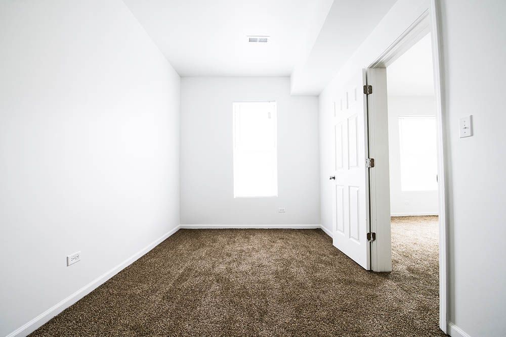 Empty room with brown carpet, white walls, and an open doorway.