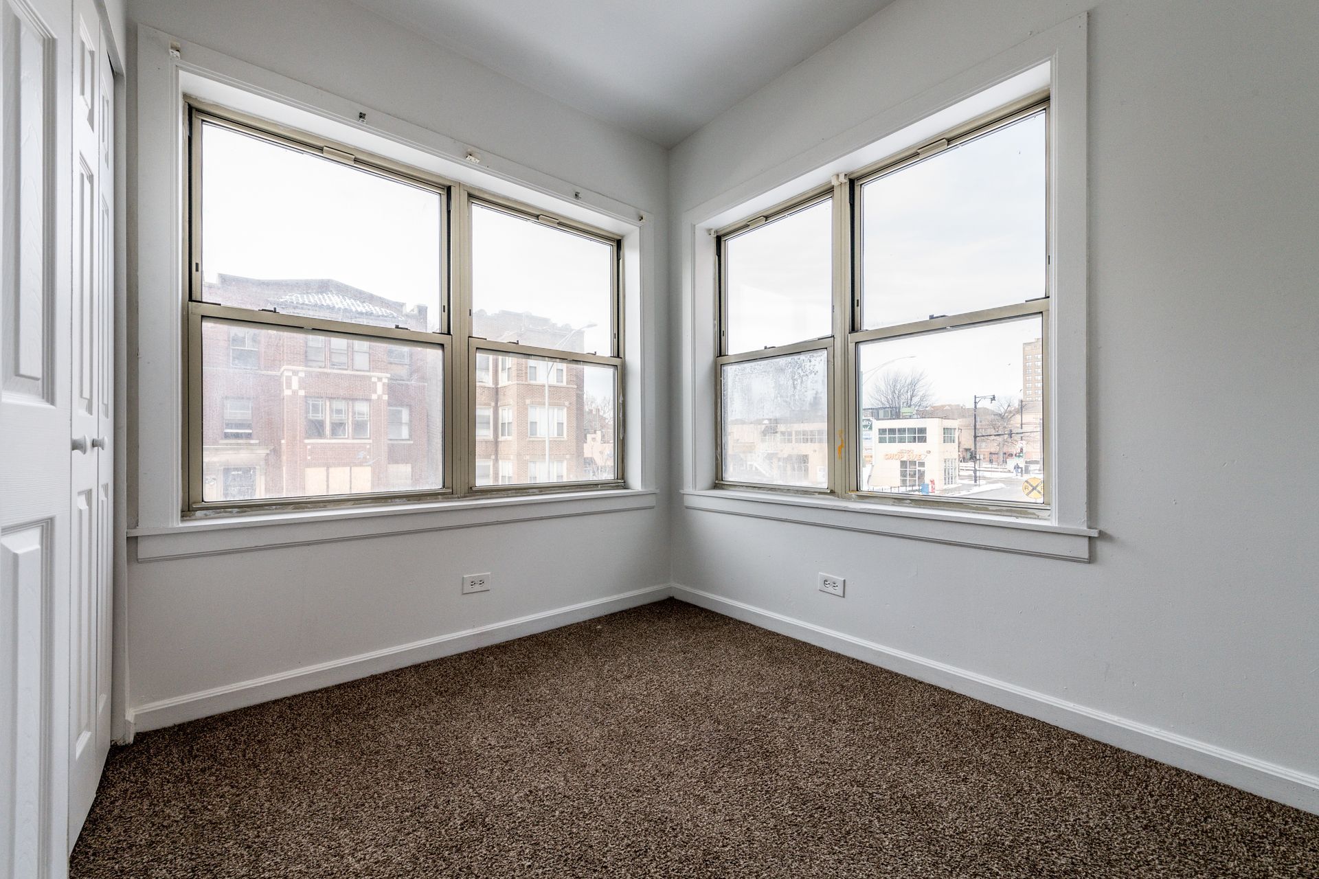 Empty room with two large windows; brown carpet, white walls and trim.