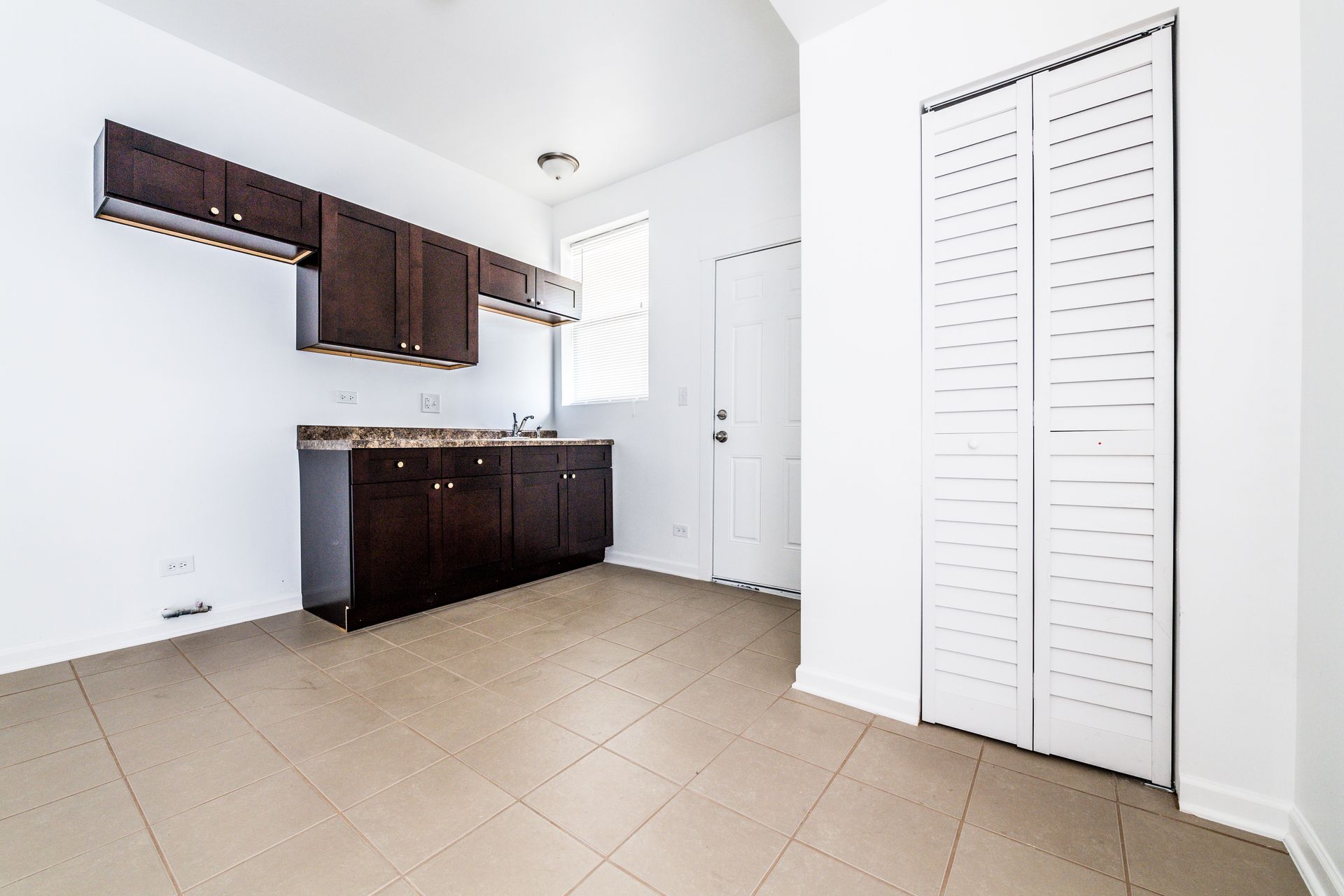 Small kitchen with dark brown cabinets, white door, and closet.