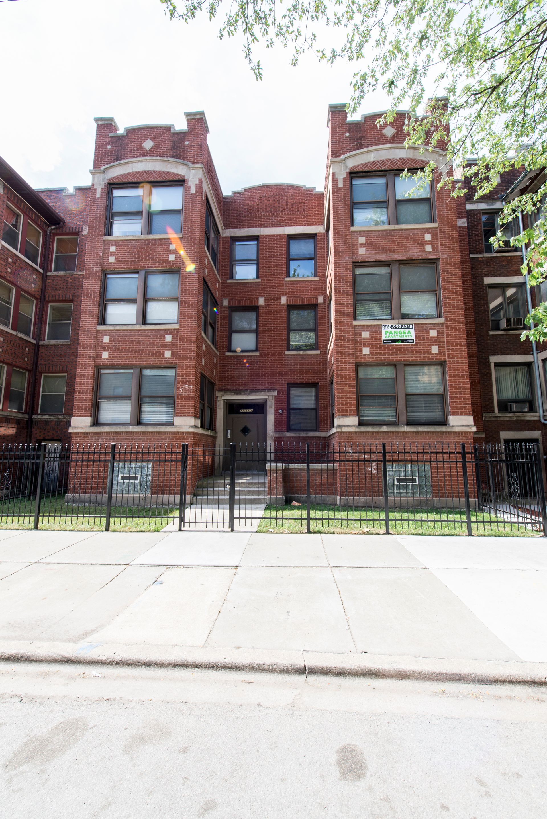 Brick apartment building with iron fence in front.