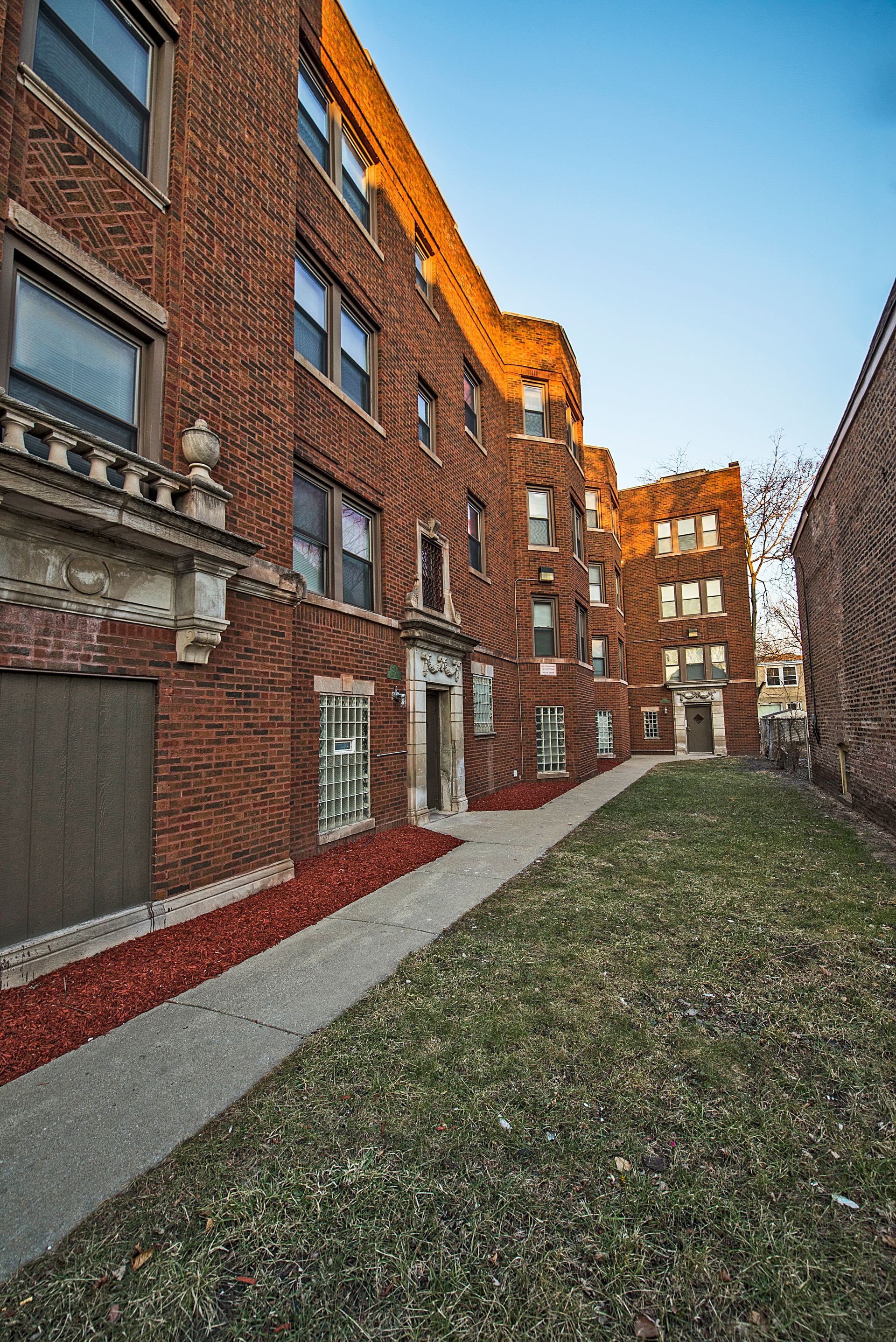 Brick apartment building with pathway and small lawn.