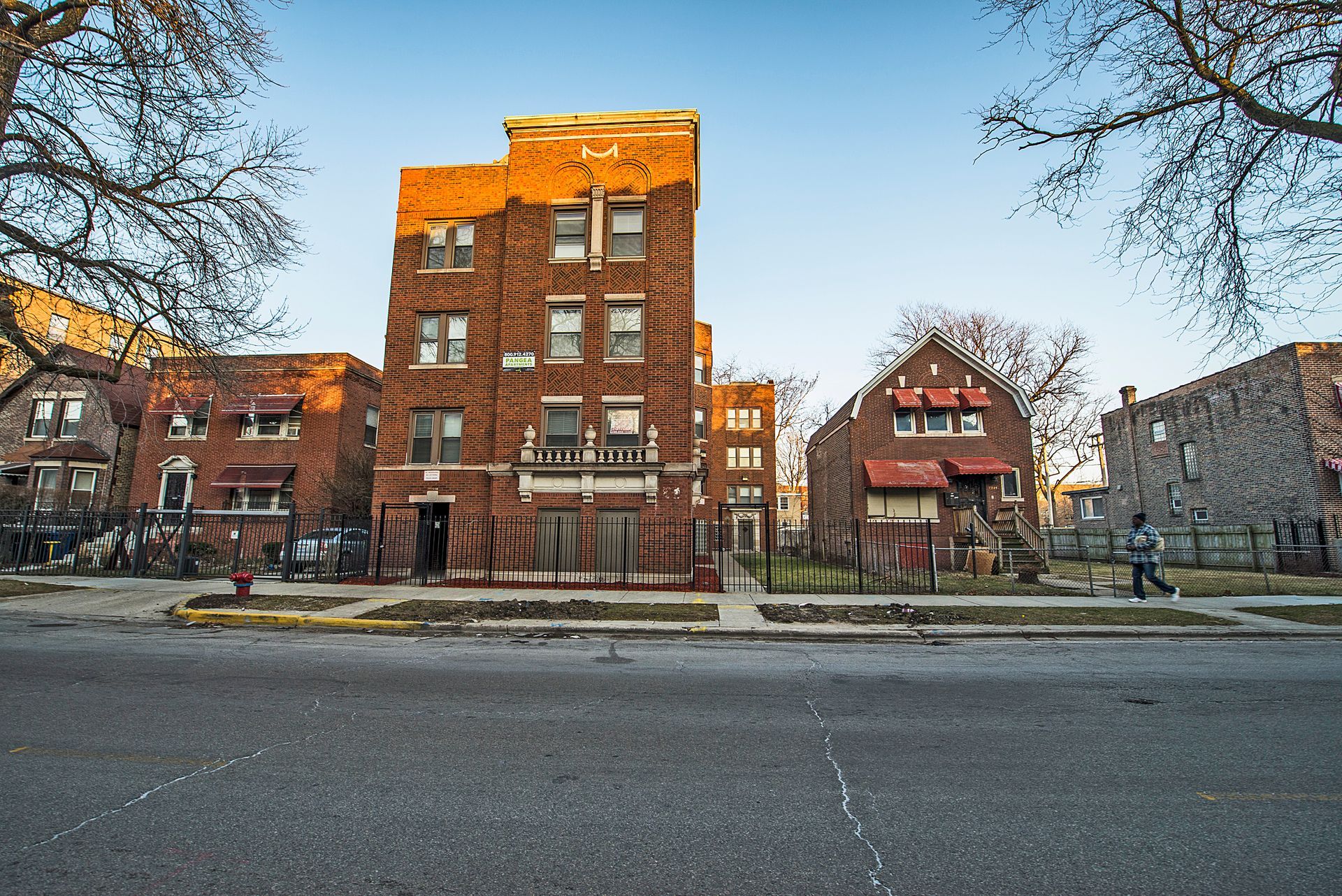 Row of brick buildings on a city street. A person walks on the sidewalk.