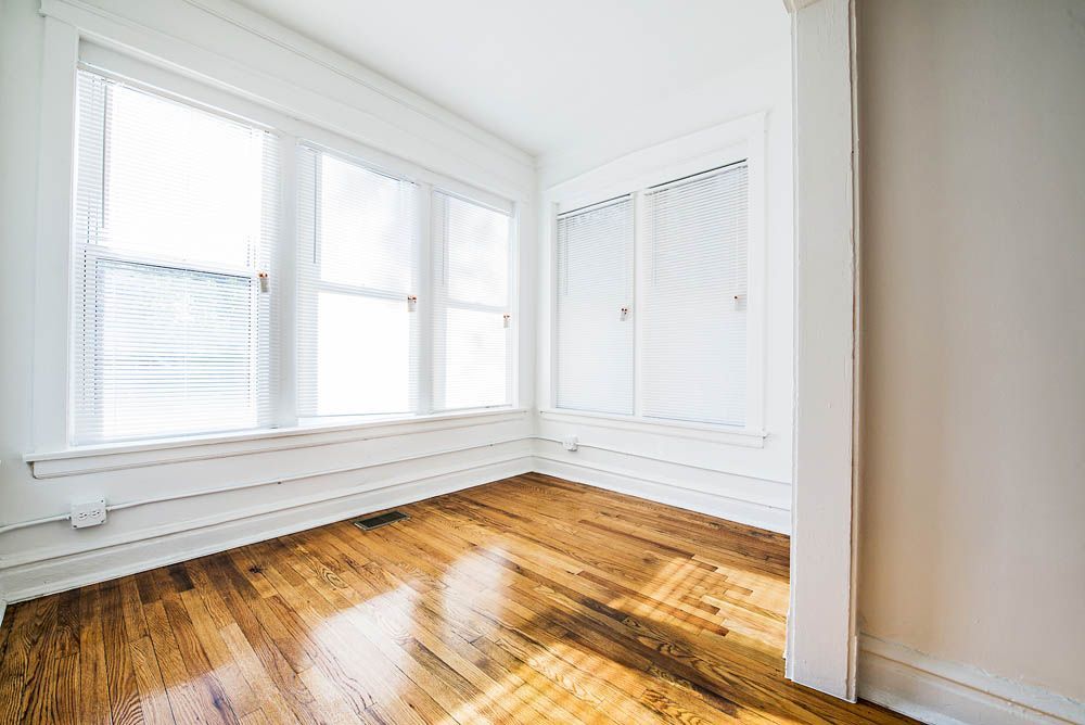 Empty room with hardwood floors, white trim, and a large window.
