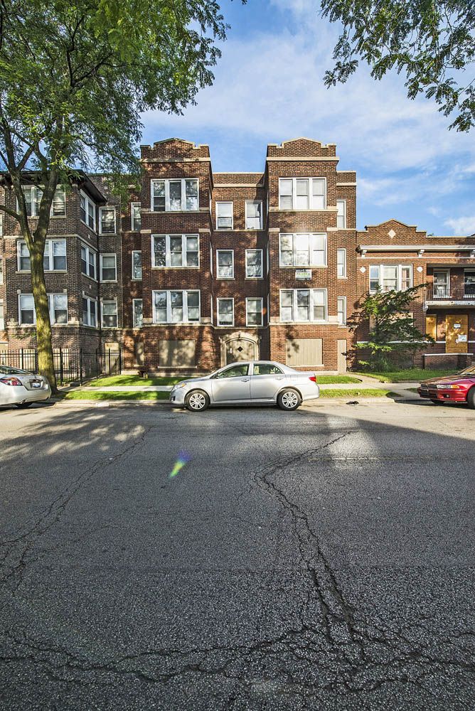 Brown brick apartment building with cars parked on the street.