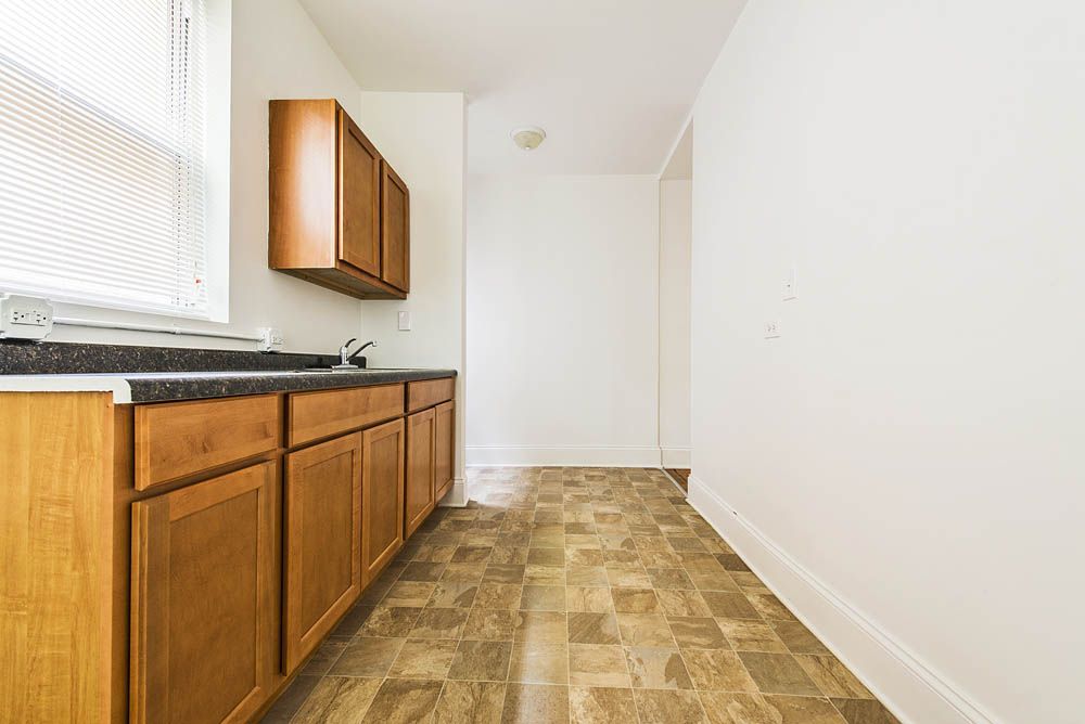 Kitchen with light brown cabinets, dark countertop, window, and tiled floor.