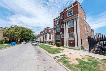 Apartment buildings with brick facade on a residential street under a blue sky.
