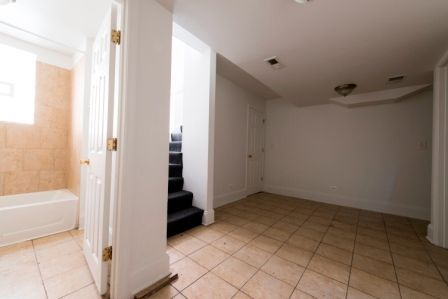 Empty room with wood floor, white walls, two white doors, and a bathroom entrance.
