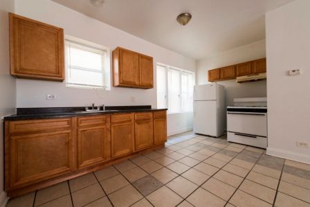 Kitchen with wooden cabinets, white appliances, and tiled floor.
