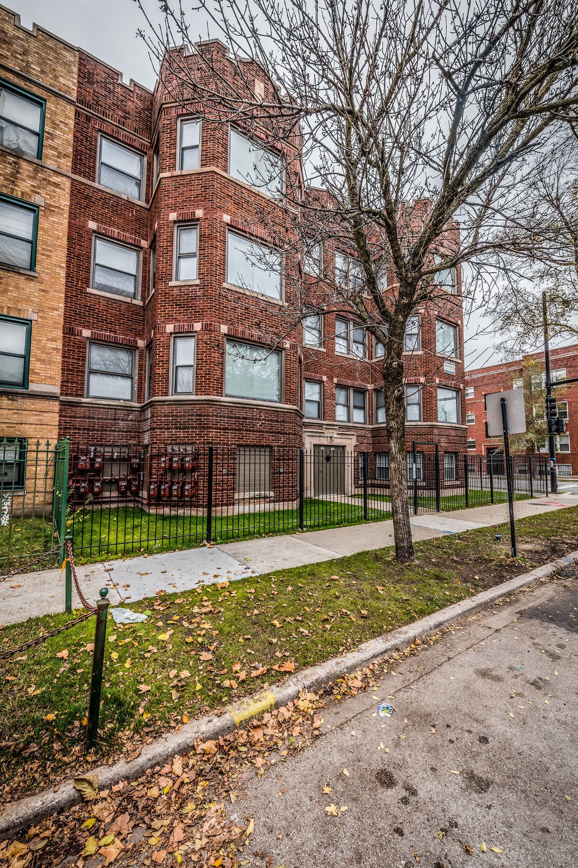 Brick apartment building with a tree in front, on a city street. Cloudy day.